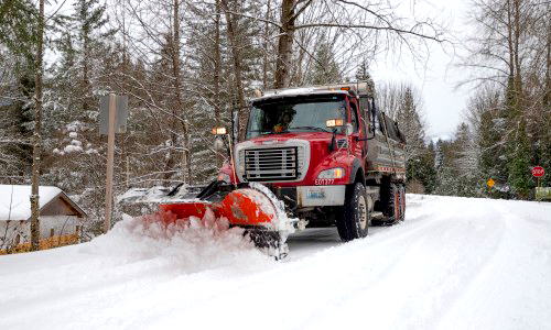 A truck with snowplow clears the road, one of many services provided by public works